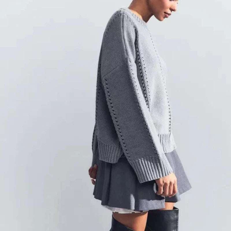 Person wearing a gray sweater over a light gray dress on a plain background