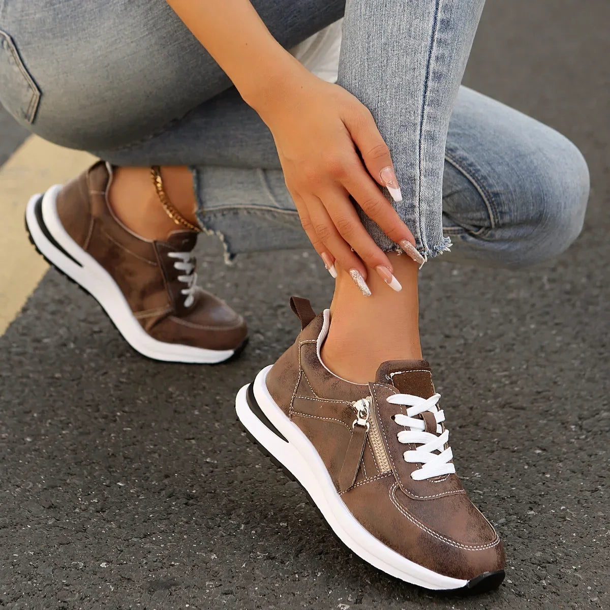 Brown sneakers with white soles worn by a person on a pavement.