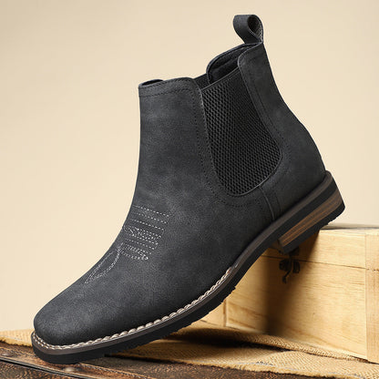 Black Chelsea boot on a wooden surface with a beige background