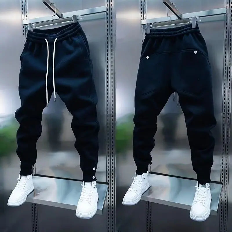 Black jogger pants with white sneakers on a metallic surface
