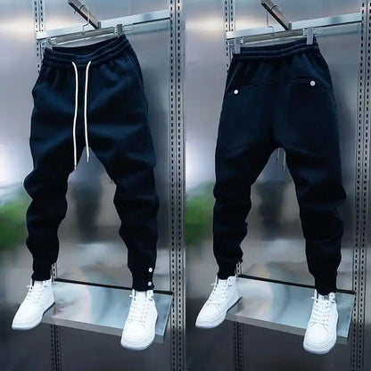 Black jogger pants with white sneakers on a metallic surface
