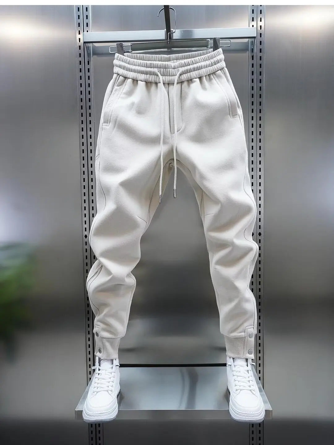 White jogger pants on a metal rack with white sneakers.