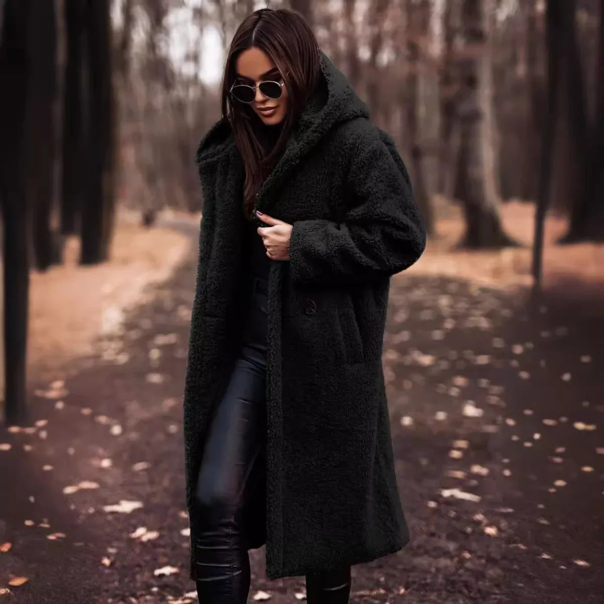 Woman wearing a long black coat in a forest setting