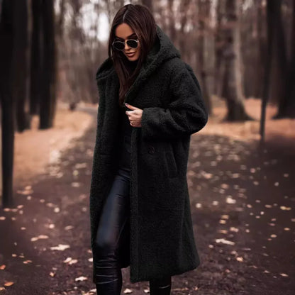 Woman wearing a long black coat in a forest setting