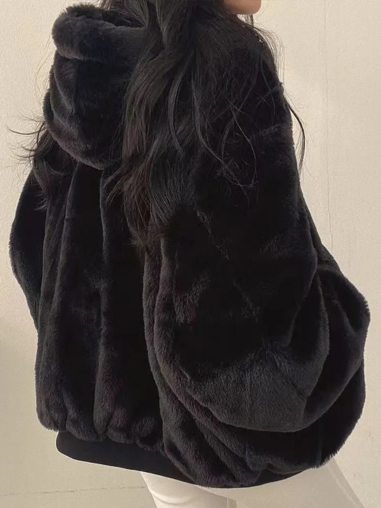 Black fur coat worn by a person on a plain background