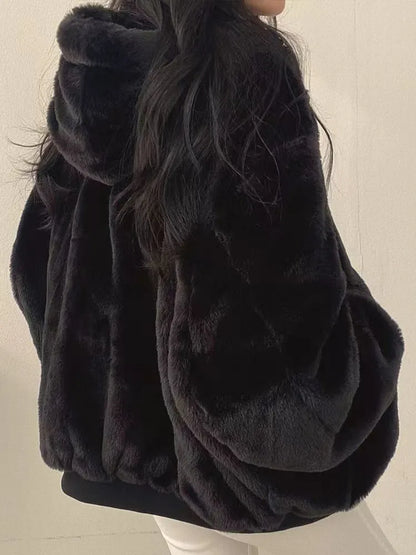 Black fur coat worn by a person on a plain background