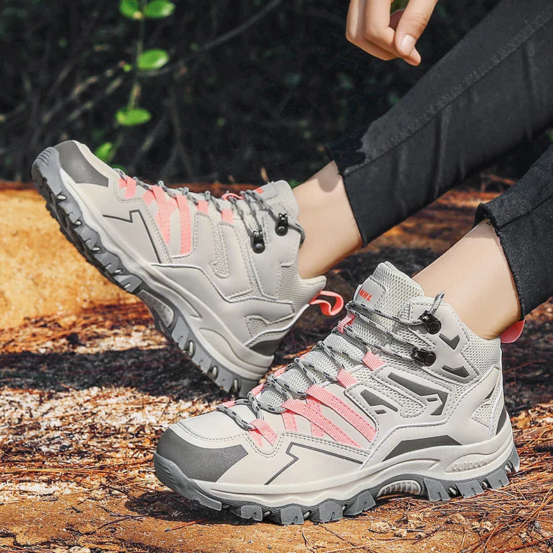 Gray hiking boots with pink accents worn by a person on a wooden surface.