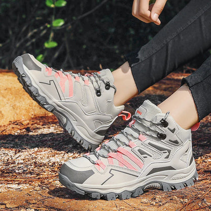 Gray hiking boots with pink accents worn by a person on a wooden surface.