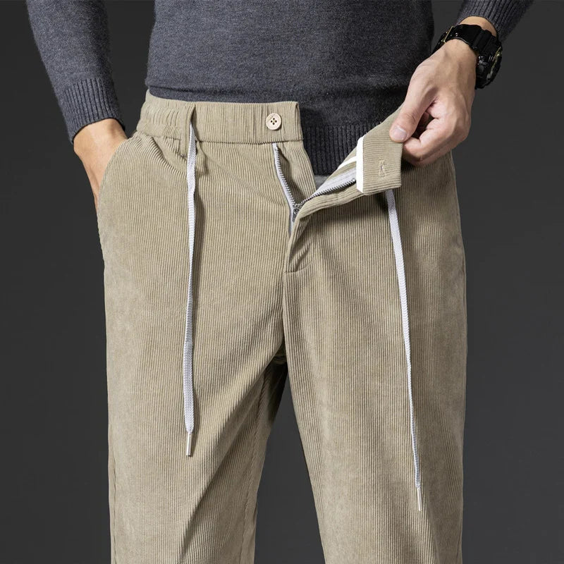 Beige corduroy pants with white drawstrings worn by a person on a dark background