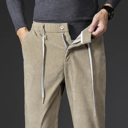Beige corduroy pants with white drawstrings worn by a person on a dark background