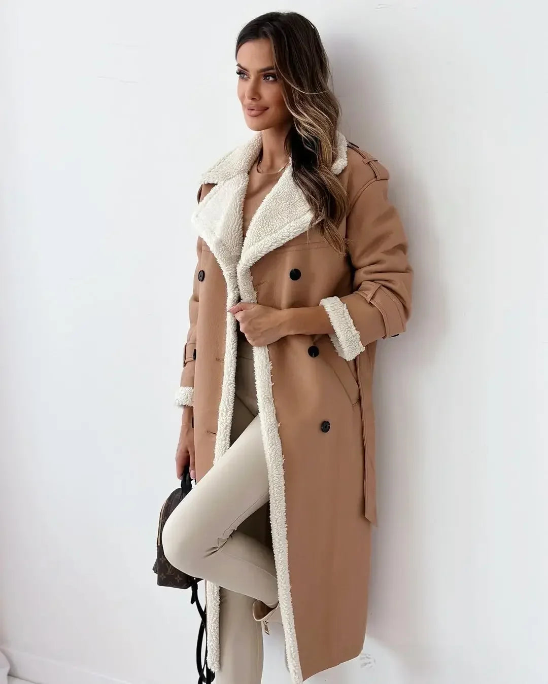 Woman wearing a brown coat with white fur lining against a white background