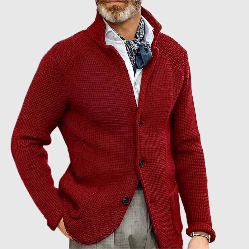 Man wearing a red cardigan over a white shirt with a patterned scarf on a light gray background