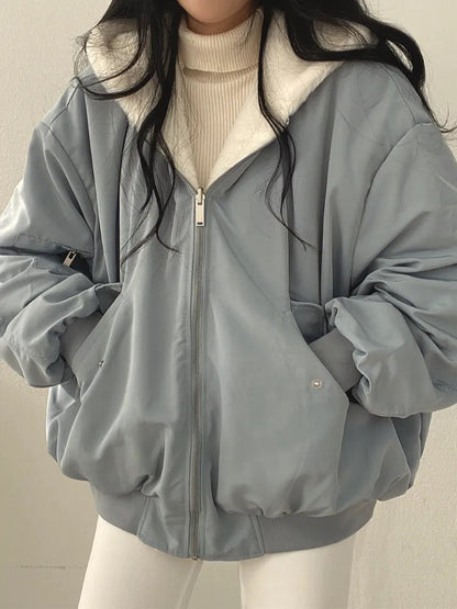 Person wearing a gray jacket over a beige sweater on a plain background
