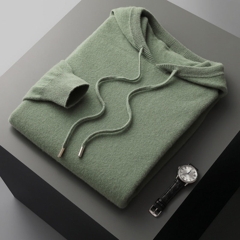 Green hoodie on a gray surface with a watch beside it