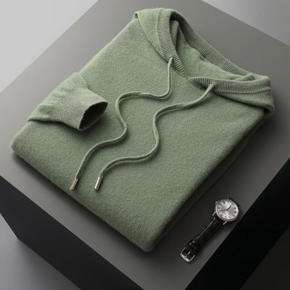 Green hoodie on a gray surface with a watch beside it