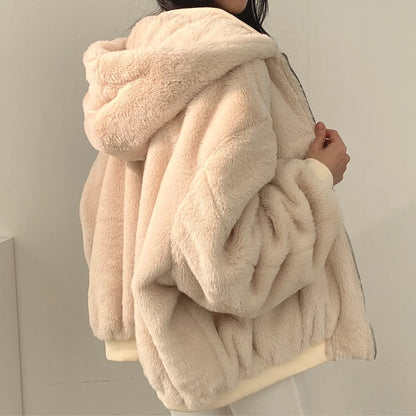 Beige fluffy coat held by a person against a neutral background