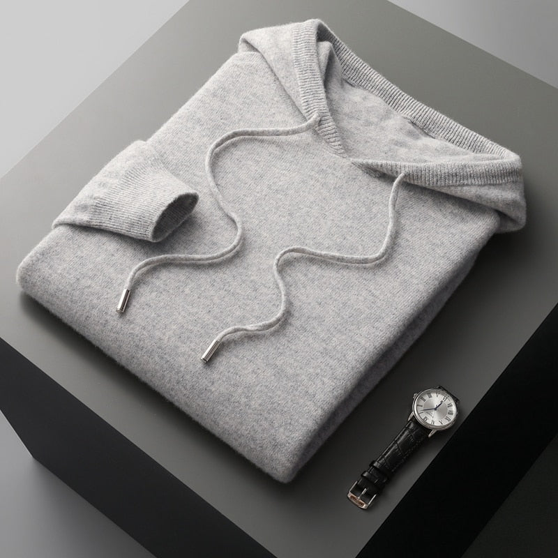 Folded gray hoodie on a dark surface with a watch beside it