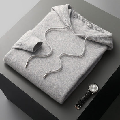 Folded gray hoodie on a dark surface with a watch beside it