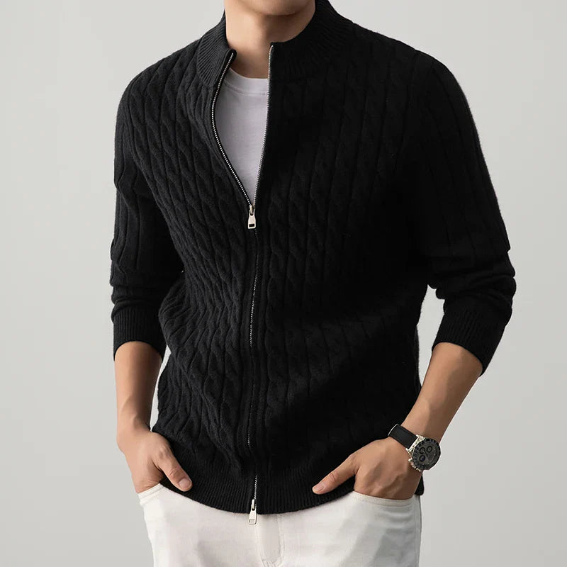 Person wearing a black zip-up sweater over a white shirt on a gray background