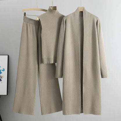 Beige outfit with a coat, pants, and sweater on hangers against a gray background