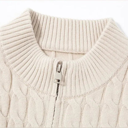 Close-up of a beige cable knit sweater with a zipper detail on a white background