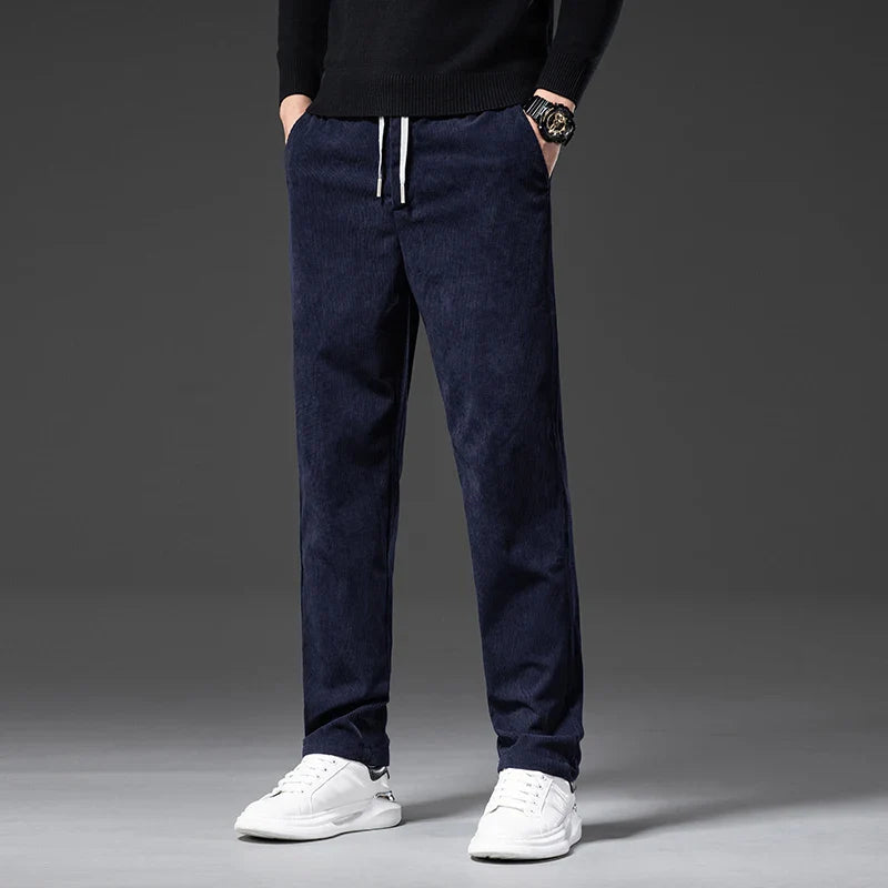 Person wearing navy blue pants and white sneakers on a gray background