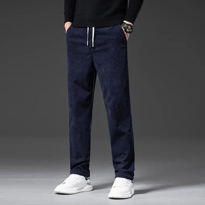 Person wearing navy blue pants and white sneakers on a gray background