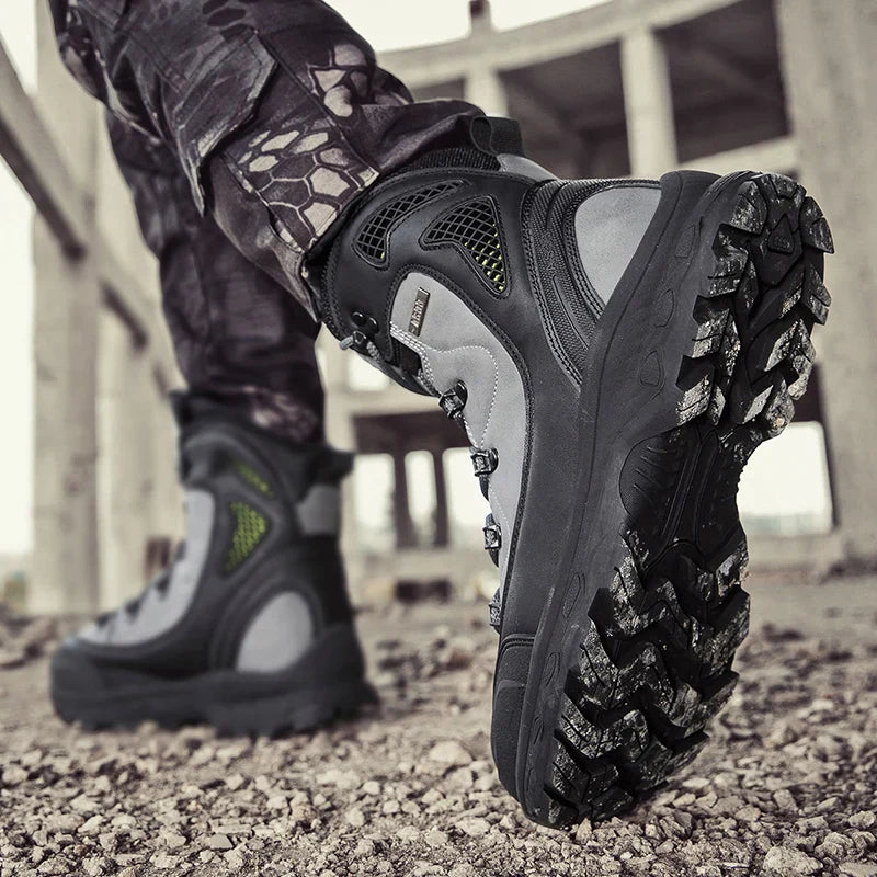 Close-up of a person wearing black tactical boots with a textured sole on a rocky surface.