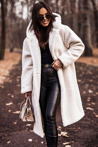 Woman wearing a white coat and black leather pants in a forest setting