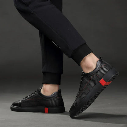 Black sneakers with red accents worn by a person on a dark background