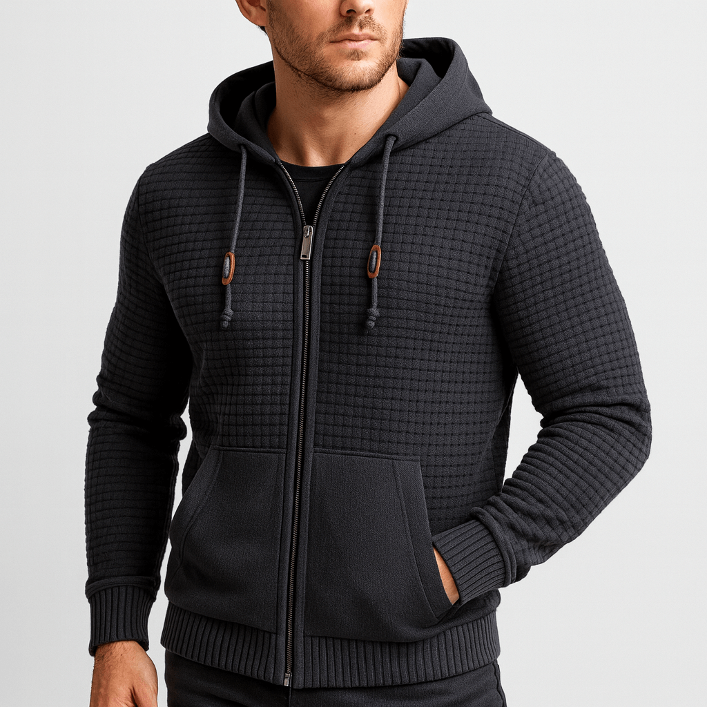 Man wearing a black textured zip-up hoodie on a light gray background