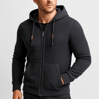 Man wearing a black textured zip-up hoodie on a light gray background