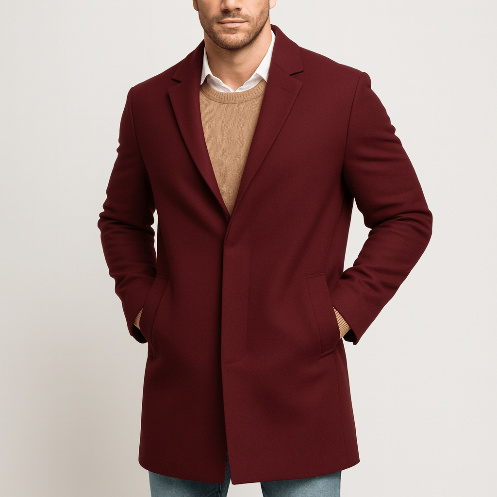 Man wearing a burgundy coat over a beige sweater on a light gray background