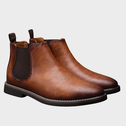 Pair of brown leather Chelsea boots on a light gray background