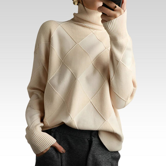 Person wearing a beige diamond-patterned turtleneck sweater with dark pants