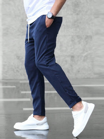 Person wearing navy pants and white sneakers on a gray floor.