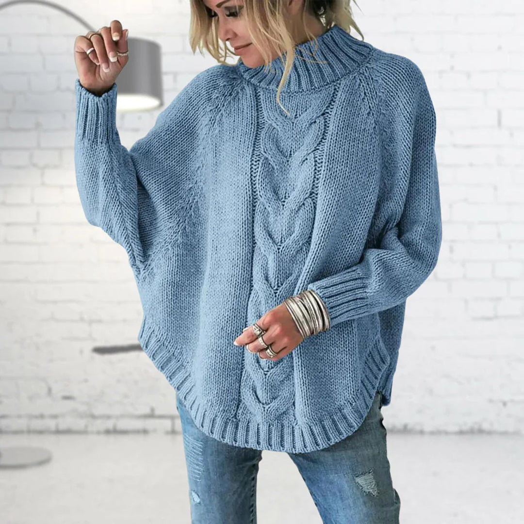 Person wearing a blue cable knit sweater in a minimal indoor setting