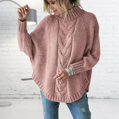 Person wearing a pink cable knit sweater with a white brick wall background