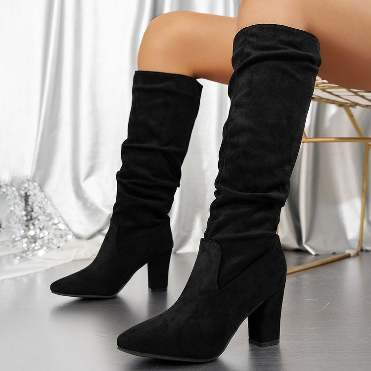 Black knee-high boots worn by a person on a neutral background