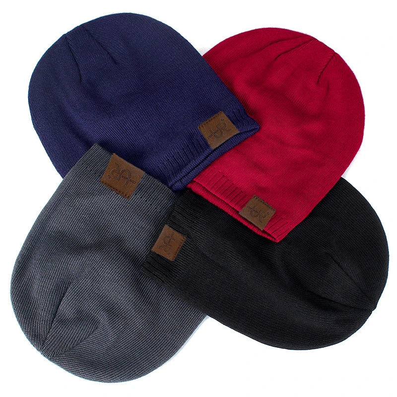 Four beanies in navy, red, gray, and black with brown patches on a white background