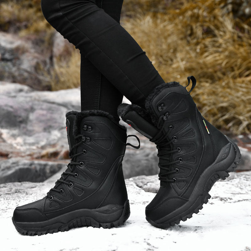 Black winter boots with fur lining worn by a person on a snowy ground.