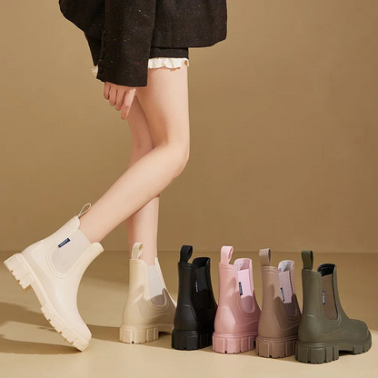 Person wearing white boots with a row of colorful rain boots on a beige background
