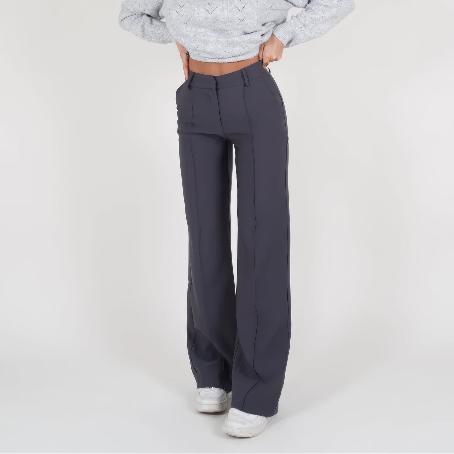 Person wearing gray high-waisted pants on a white background