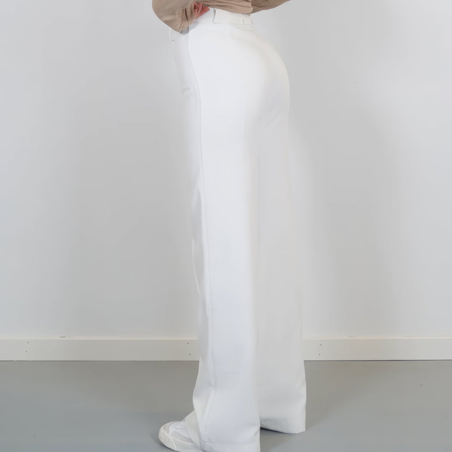 Person wearing white pants against a plain white background