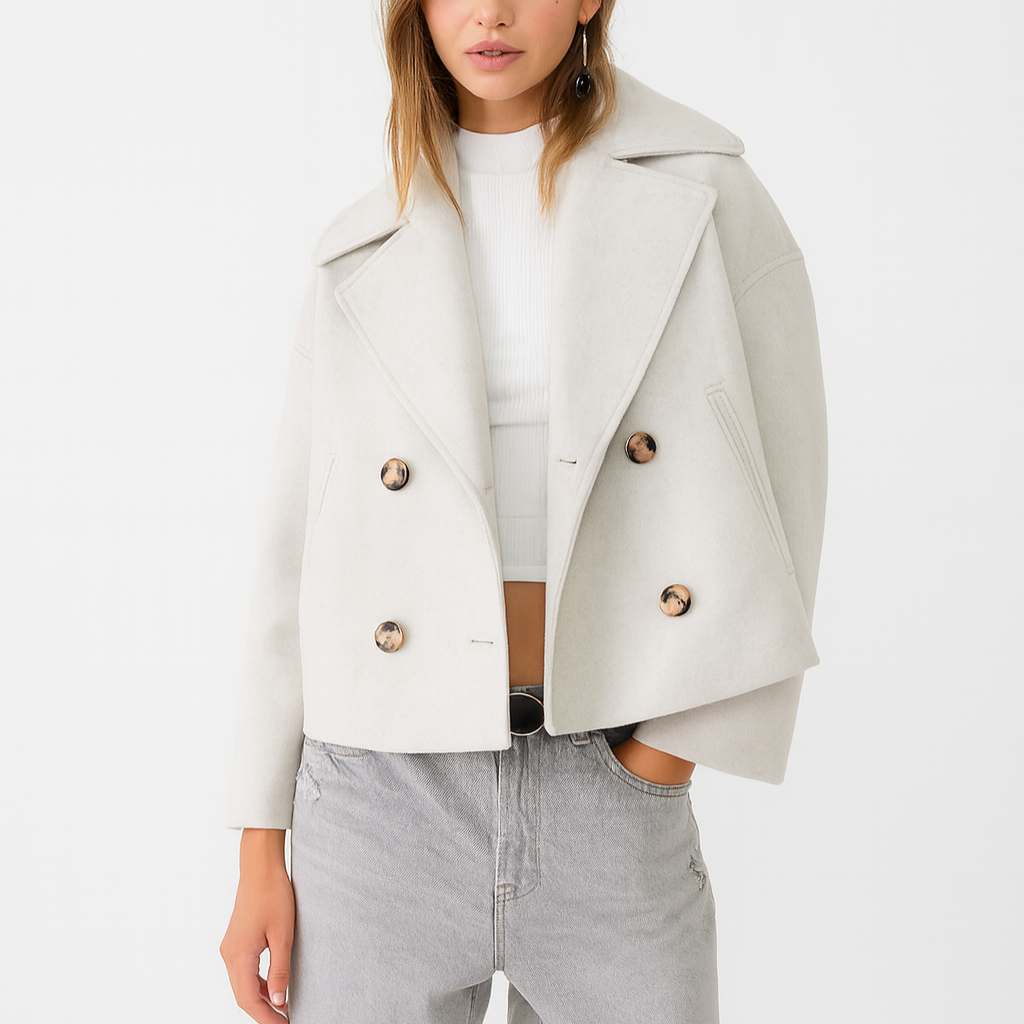 Woman wearing a light gray blazer with gold buttons on a white background