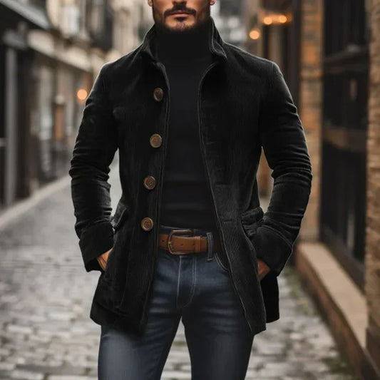 Man wearing a black coat and jeans standing on a street.