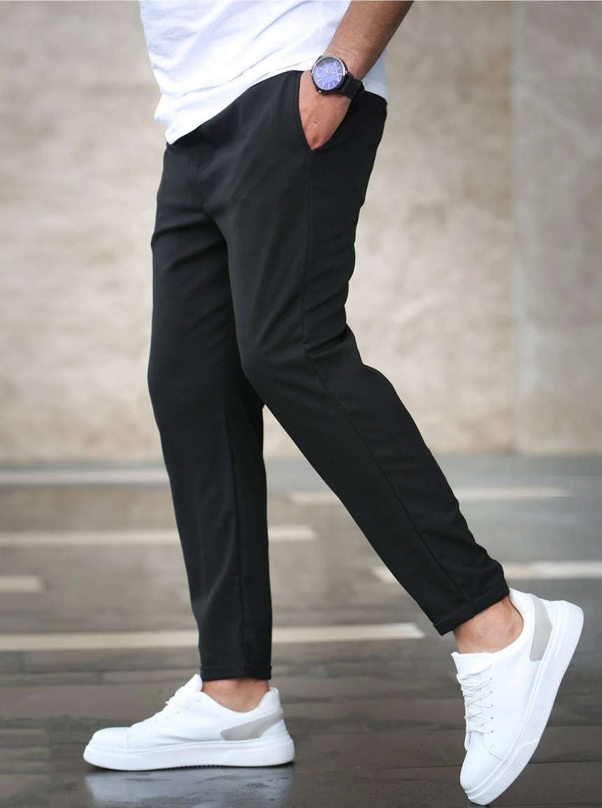 Person wearing black pants and white sneakers on a blurred background