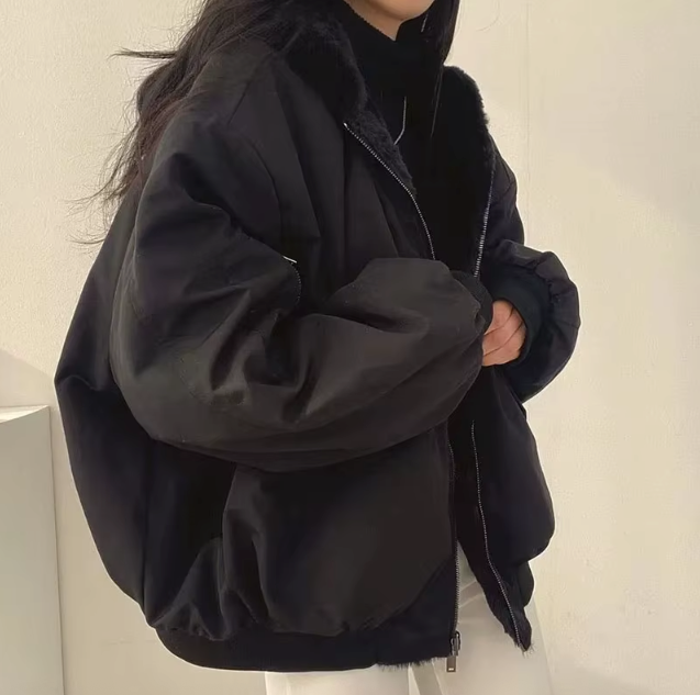 Person wearing a black jacket against a plain background