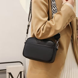 Person holding a black handbag with a neutral background