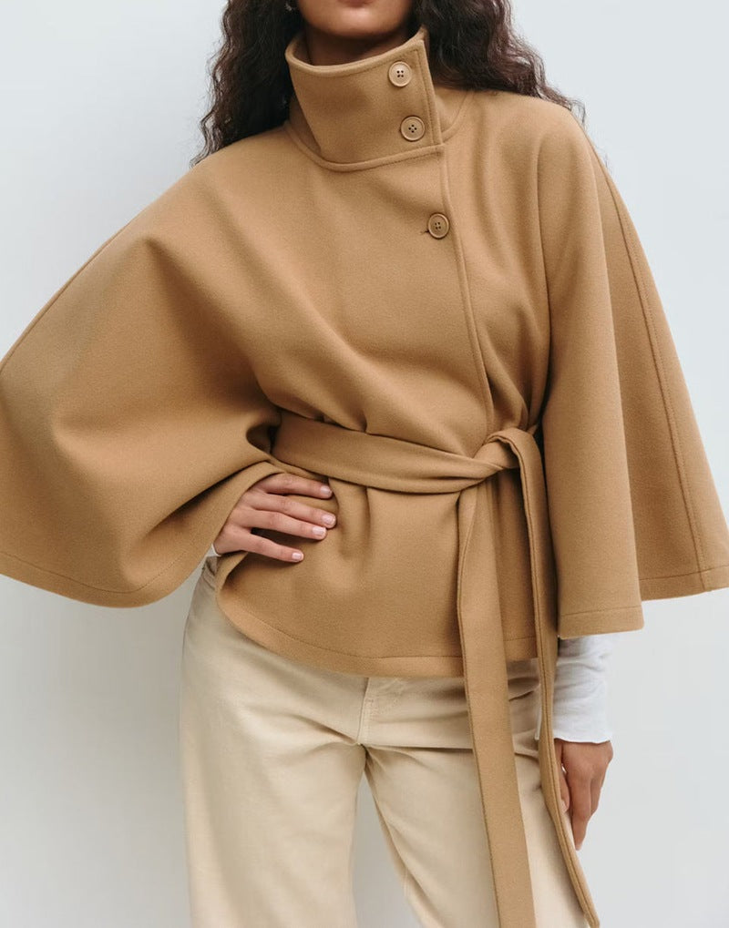Person wearing a beige cape with a plain background